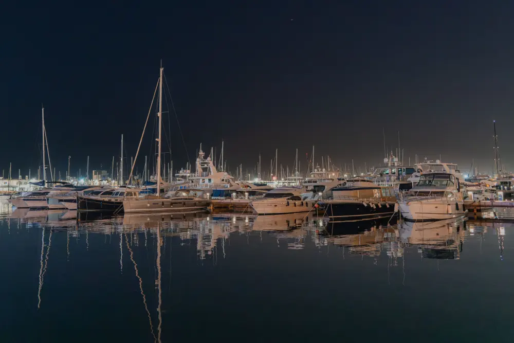 Yachts moored in an illuminated marina at night